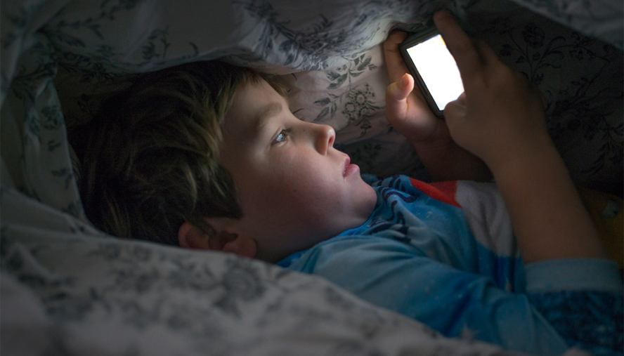 Child looking at a phone screen before bed
