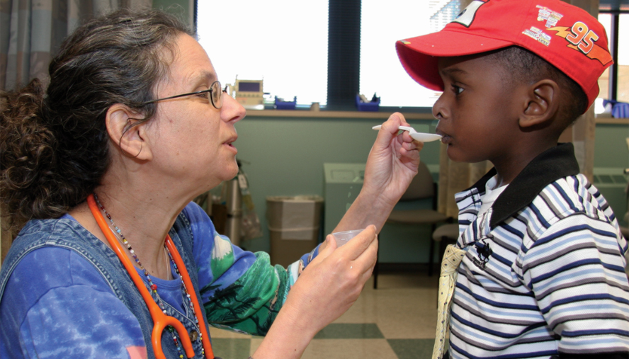 Doctor feeding child patient with a spoon