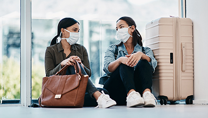 Stay on Track with Safe Travel: Two women at the airport wearing facemasks